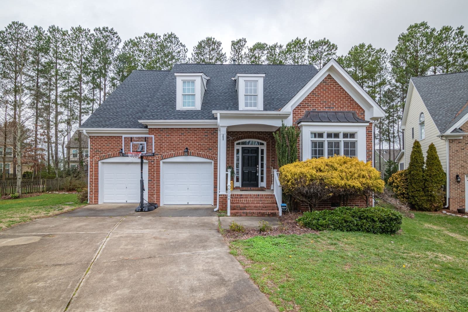 Brick two-story home with white garage doors and a long concrete driveway
