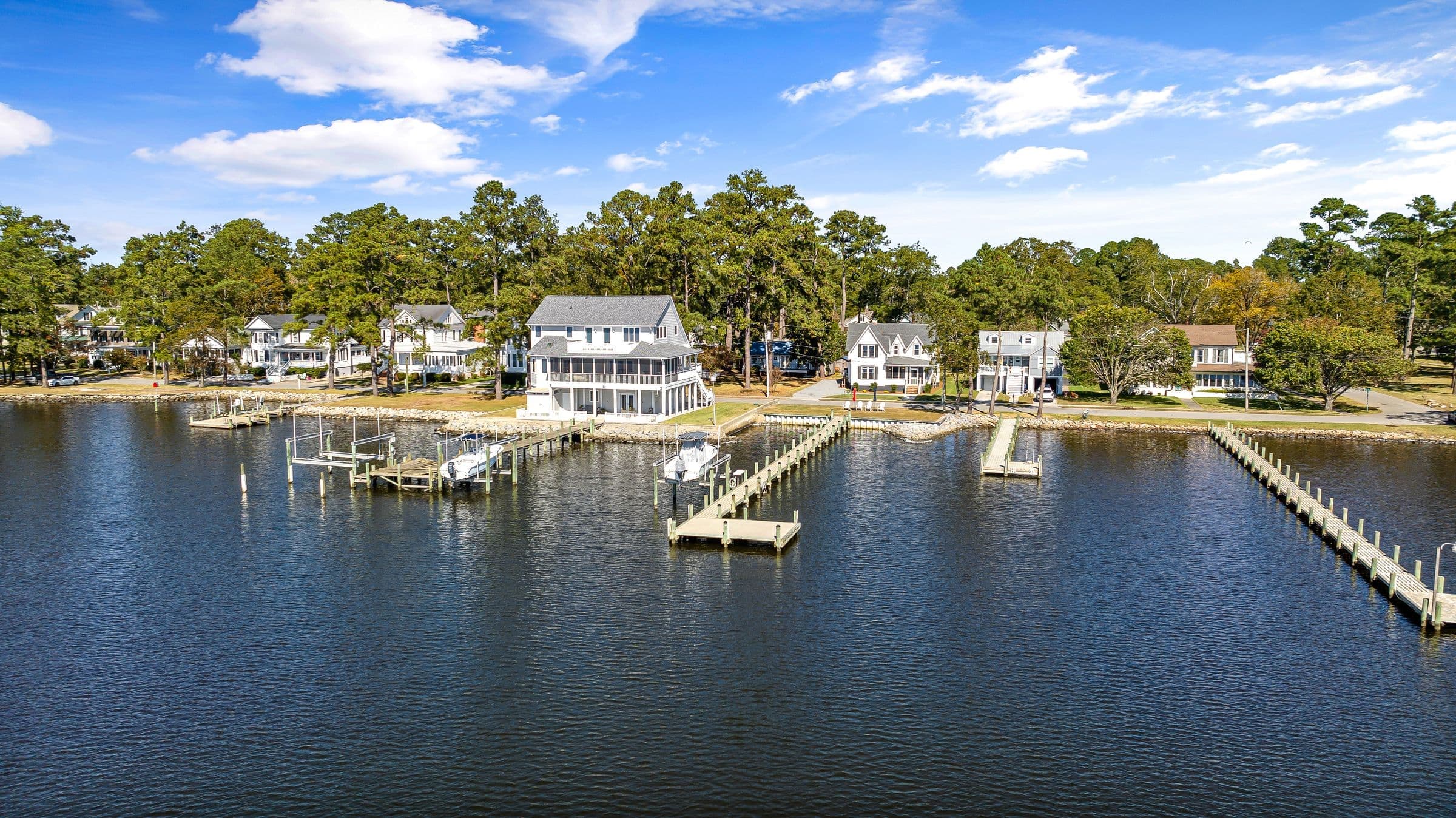 Aerial view of lakefront homes with boat docks and lifts on calm water