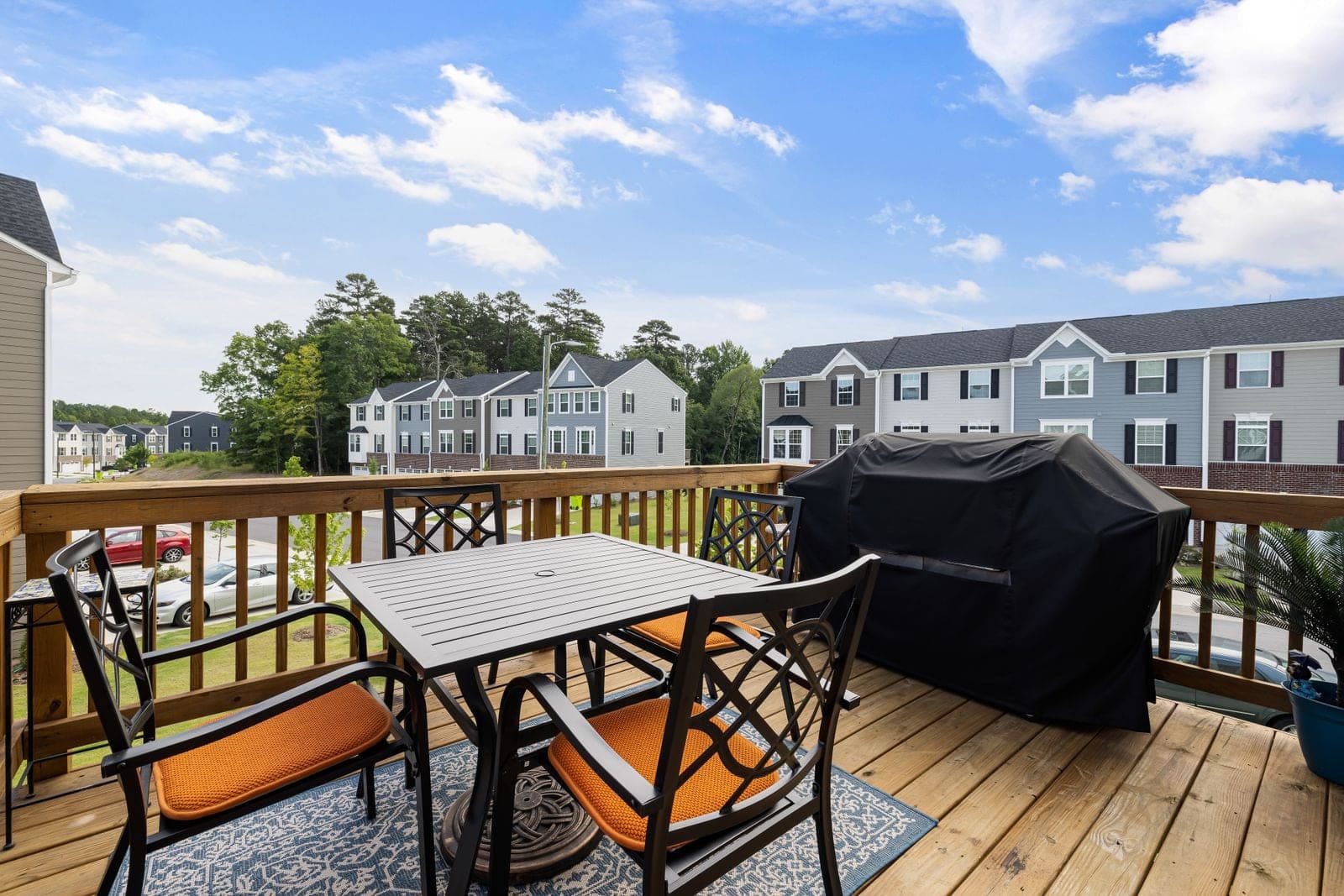 Clean wooden deck with a patio table, chairs and a covered grill